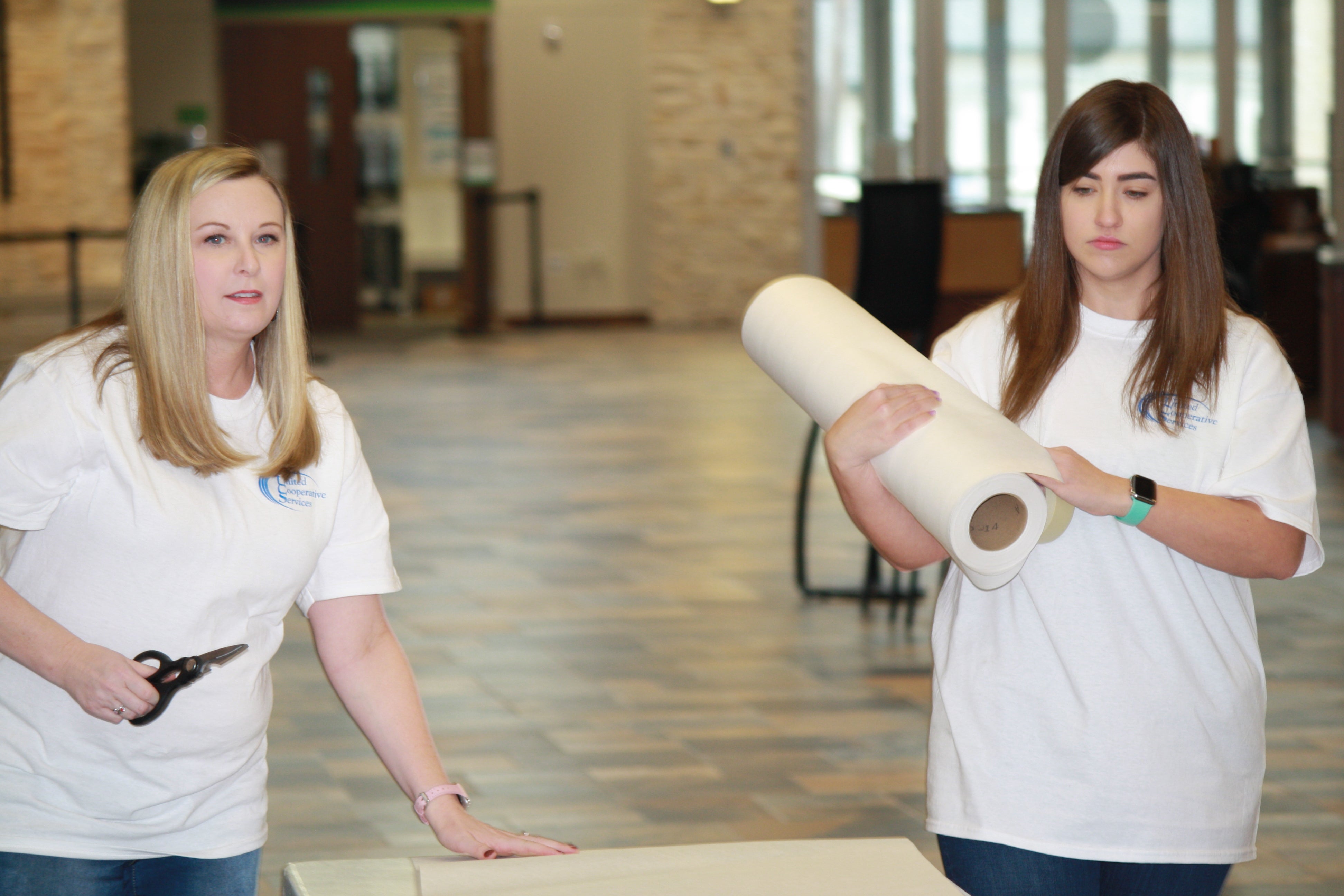 Lindsey Mobley, left, and Kennedy Curlee cut butcher paper for dinner preparations at Pathway Church