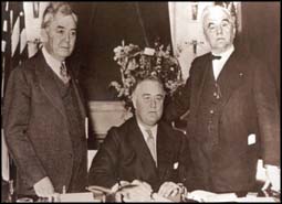 Franklin Delano Roosevelt (center) signs the Rural Electrification Act with Representative John Rankin (left) and Senator George William Norris (right)
