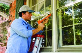 Stock image of man caulking his windows