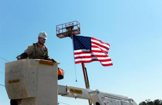 Image of lineman in bucket truck with American flag
