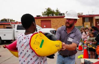 Image of United employee helping student try on PPE