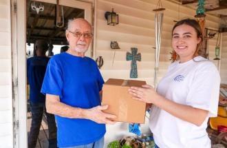 Image of woman handing man a meals on wheels box of food