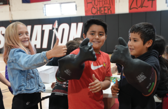 School age children at Three Way ISD try on lineman's gloves. 