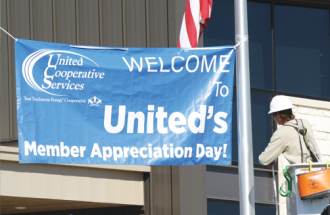 A BANNER DAY—Christian Ryon, apprentice lineman I, puts up a banner at United’s Mansfield office, welcoming members to the Member Appreciation Day lunch.