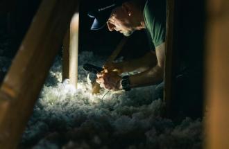 Image of person measuring insulation level in attic